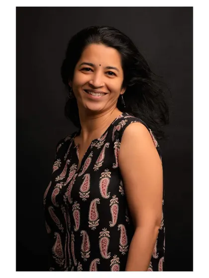 A simple and honest portrait of a woman with a genuine smile. The black background and natural expression make this a timeless headshot.