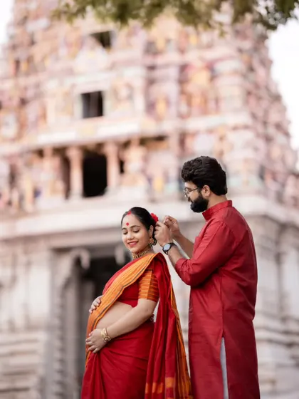 A tender moment between the couple at the temple, as he gently places a flower in her hair, a beautiful detail in their traditional maternity photoshoot.
