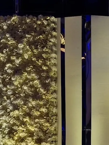 A detail shot of a floral wall made of white and yellow roses, used as a photo backdrop for a cocktail party.