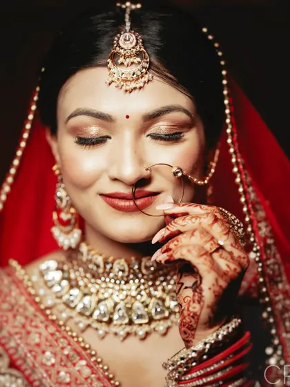 A classic bridal beauty shot, focusing on the bride's flawless makeup, intricate jewelry, and serene expression.