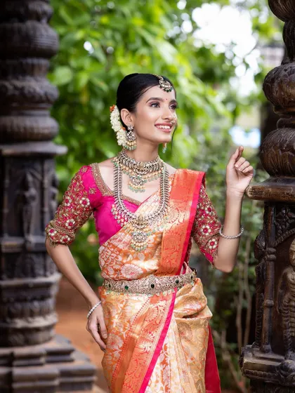 This silver-finish set with light green stones offers a softer, more delicate look. It pairs beautifully with this gold and pink saree for a sophisticated reception style.