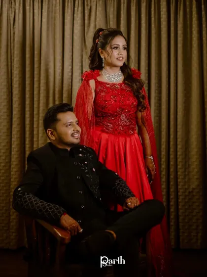 A powerful and regal couple portrait from their sangeet. The bride's red gown with a cape is a showstopper.