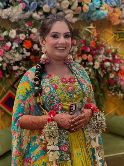Holding her phone but still posing like a star. This image shows the complete mehendi look, from the floral kaleeras to the braided hairstyle.
