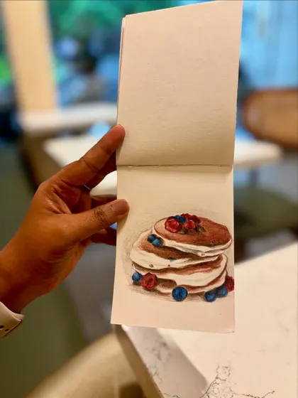 Holding up my sketchbook to show the pancake drawing.