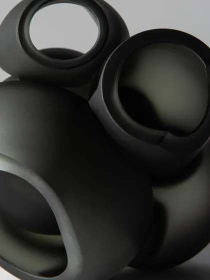 A detailed shot of the matte, dark grey finish of the Bocci 100 series pendants, highlighting their smooth, sculptural quality.