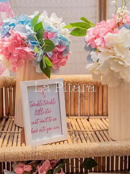 A charming detail shot of a 'Twinkle twinkle little star' sign next to vases of pink and blue hydrangeas.