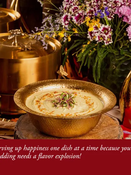 A close-up of our hammered-brass serving bowl filled with a creamy dish, set against a backdrop of vibrant floral arrangements and elegant decor, highlighting our attention to detail.
