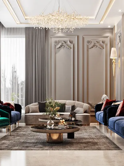 A full view of a formal living room with classic European design influences, including wall mouldings and sconce lighting, paired with modern velvet sofas in bold blue and green.