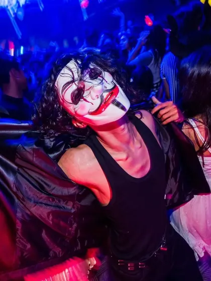 A guest in a V for Vendetta mask at a Halloween party.