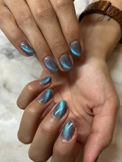 This shot captures the beautiful shimmer of the teal cat-eye polish against the client's skin tone.