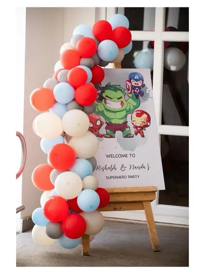 A 'Welcome to the Superhero Party' sign, featuring cute versions of the Hulk, Iron Man, and Captain America, framed by a red, white, and blue balloon garland.