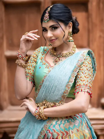 A close-up of the sea-green blouse, showcasing the intricate, multi-colored threadwork that complements the lehenga.