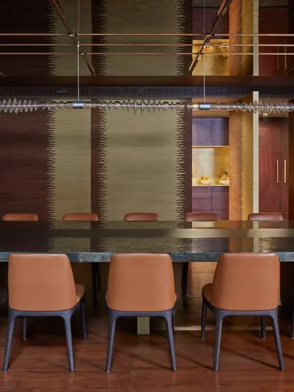 The dining room at the Baid Residence, where a fluted brass and wooden door creates mesmerizing patterns. The space is completed with a modern table and a distinguished Red Dot Awarded light.