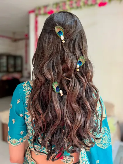 A unique hairstyle for a pre-wedding ceremony, featuring soft waves and beautiful peacock feather clips.