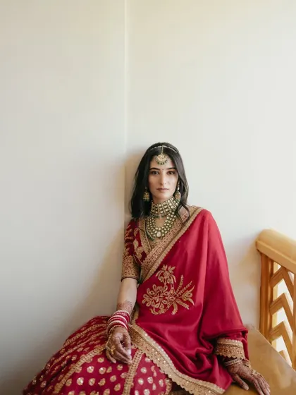 A striking portrait of Nikita in her red bridal attire. The direct gaze and rich colors create a powerful and confident image.