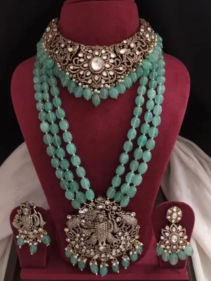 This pastel green Victorian set combines a floral choker with a traditional Krishna pendant on the long necklace, creating a unique and elegant fusion look.