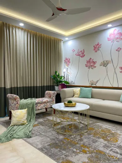 This modern contemporary guest room is designed to feel like a luxury retreat. A hand-painted lotus mural serves as a beautiful accent wall behind a comfortable sofa, complemented by a floral chaise lounge and a marble-top coffee table with a gold base.