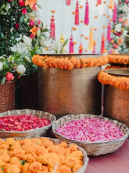Baskets of colorful flower petals, including pink, orange, and red, are ready for the Haldi celebration, adding to the vibrant atmosphere.