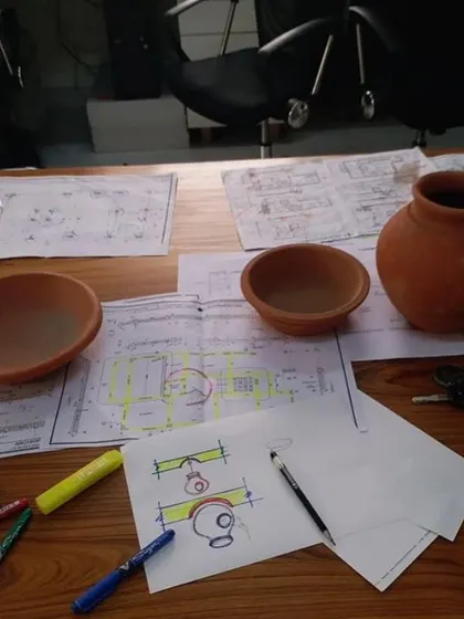 The design process involves physical models and material samples, like these earthen pots, to translate sketches into tangible reality.
