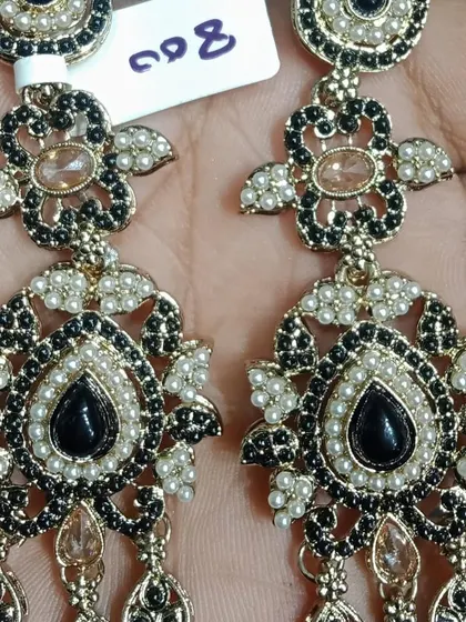 A pair of stunning black and gold earrings with pearl detailing. The intricate design and colour combination make these a very unique and elegant choice for evening wear.