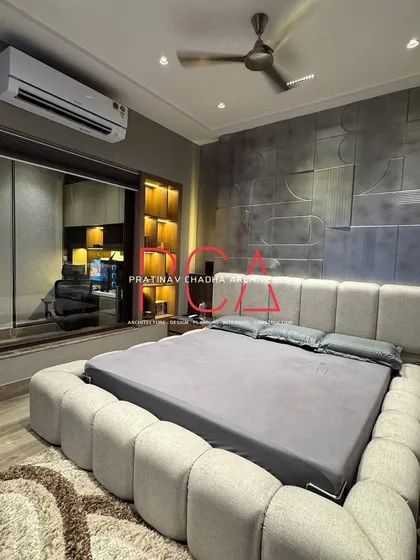 An angled shot of the son's bedroom, emphasizing the plush, oversized frame of the bouclé bed.