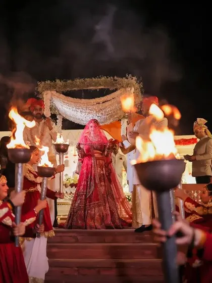 The bride's grand entry, guided by performers with torches. This dramatic entrance creates a powerful and unforgettable visual for your wedding album.