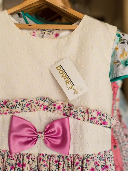 Another detailed shot of the white and pink floral dress, focusing on the vibrant pink bow and delicate floral pattern.