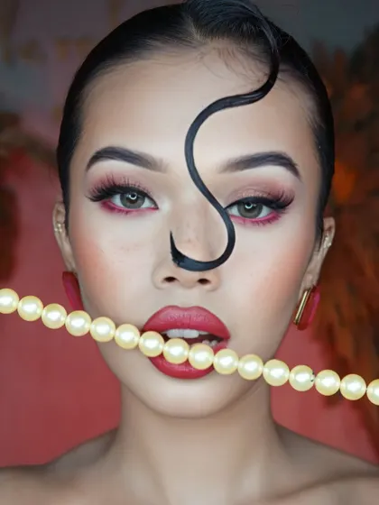 Adding a touch of classic elegance with pearls, this pose contrasts the modern, edgy makeup with a timeless accessory.