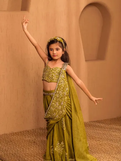 The elegant drape and hand embellished details of this green saree are visible in this graceful pose.