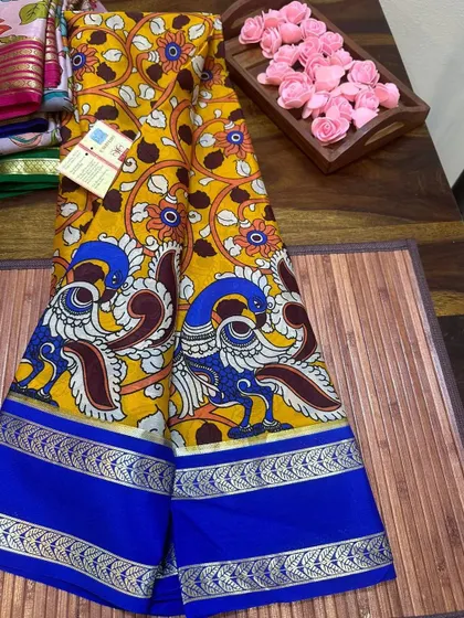 A traditional peacock motif Kalamkari print on a yellow Mysore silk saree with a blue border.