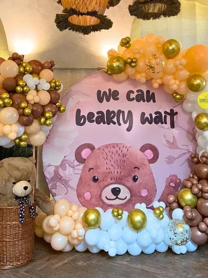 We can "bearly wait"! This round backdrop with a cute teddy bear graphic and a mix of brown, beige, and gold balloons was the centerpiece for an intimate and cozy baby shower.
