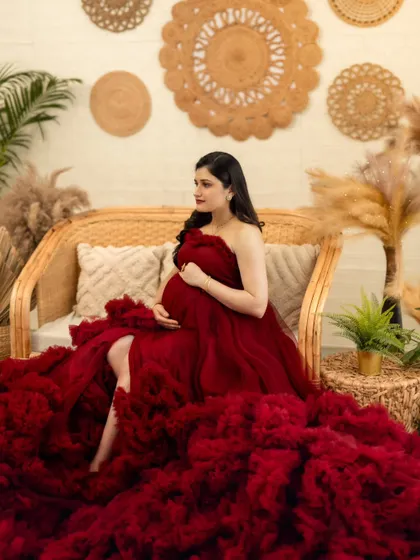 A graceful pose on our cane sofa, with the rich red gown flowing beautifully around the expecting mother.