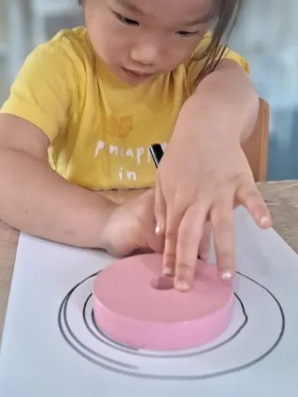 Using a foam ring as a guide, a child traces another layer of the Earth. We use various materials to make learning multi-sensory and engaging.