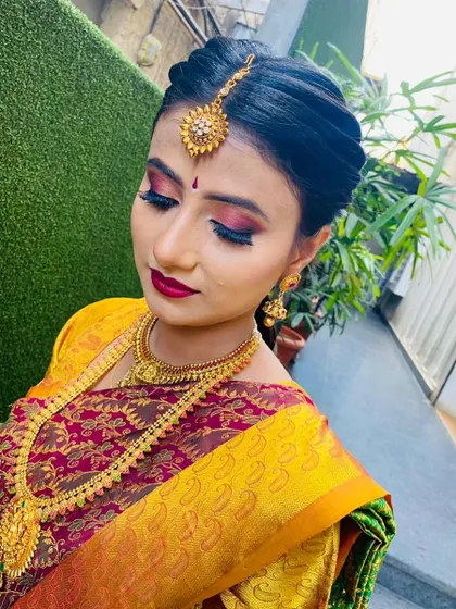A close-up of a South Indian bridal makeup look. I used a vibrant red and gold eyeshadow combination with a bold red lip, paired with a traditional puff hairstyle and maang tikka.