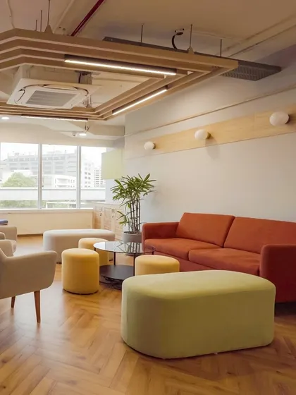 A spacious lounge area designed for relaxation and informal team gatherings. The combination of herringbone wood flooring, comfortable sofas, and varied seating creates a warm, residential feel within the office.