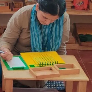 A parent uses the pegboard, a material that develops fine motor control and the pincer grip needed for writing. Experiencing this intense focus helps you appreciate the effort and concentration your child brings to their work.