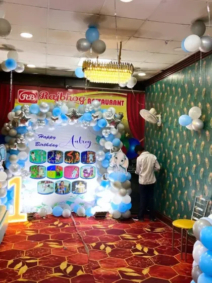 A wide view of the restaurant venue decorated for the elephant-themed first birthday, showing the main backdrop, seating area, and ceiling balloon bunches.