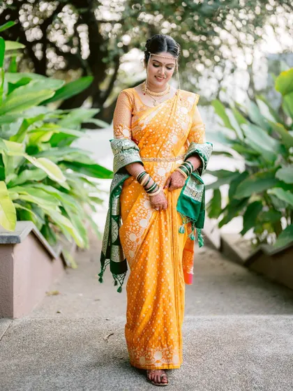 A graceful full-length portrait of the bride, Mansi, walking in her beautiful yellow wedding saree.