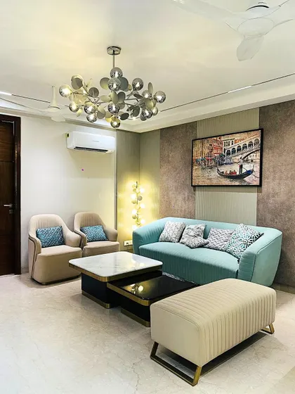 A beautiful living room setup featuring a comfortable light blue sofa, nested coffee tables with marble and black finishes, and a striking modern chandelier that adds a touch of artistry.
