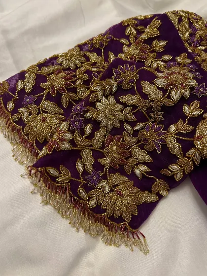 This purple net blouse was a joy to create for my dear client Sowmya's baby shower. The sheer sleeves are adorned with delicate, hand-embroidered floral vines in gold threadwork, creating a look of ethereal elegance for her special day.