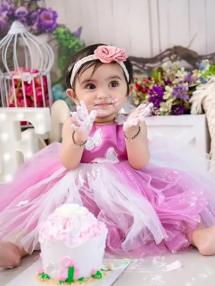 Clap for the cake! This action shot captures the excitement and anticipation of a first birthday cake smash.