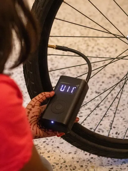 A student uses a digital pump to inflate a bicycle tire to the correct pressure. This teaches them about proper maintenance and the importance of using the right tools for the job.