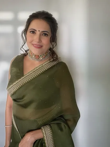 A portrait of the client, looking radiant and confident in her elegant green saree and soft, timeless makeup.