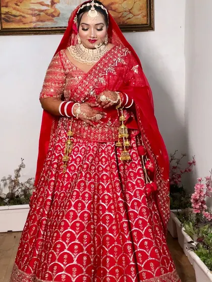 A confident pose from the bride, showing off her entire red bridal outfit and the radiant makeup that completes the look.