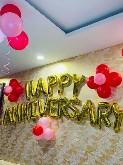 A simple anniversary wall decoration. This includes 'Happy Anniversary' foil letters with small clusters of red and pink balloons.