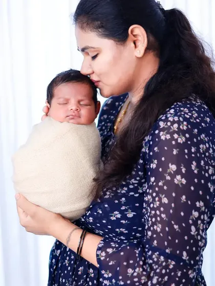 A mother holds her swaddled newborn close, capturing the quiet, loving bond in the early days.