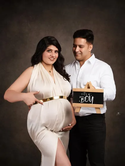 A fun and happy gender reveal moment. The mom-to-be points to her bump as her partner holds the 'It's a Boy' sign, capturing their shared excitement.