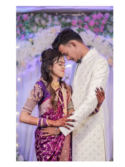 An intimate portrait with the couple in a close embrace, foreheads touching. The soft lighting and floral background create a deeply romantic atmosphere.