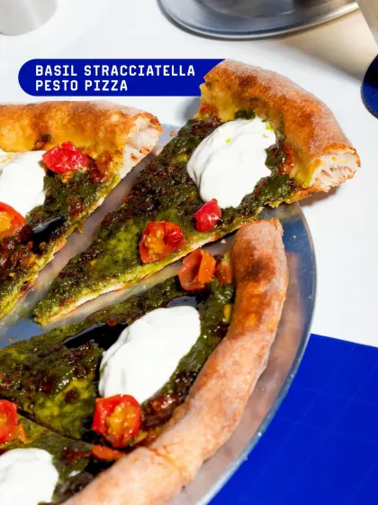 A slice of my Basil Stracciatella Pesto Pizza. This pizza is fresh and vibrant, with a rich basil pesto base, sweet cherry tomatoes, and creamy stracciatella.