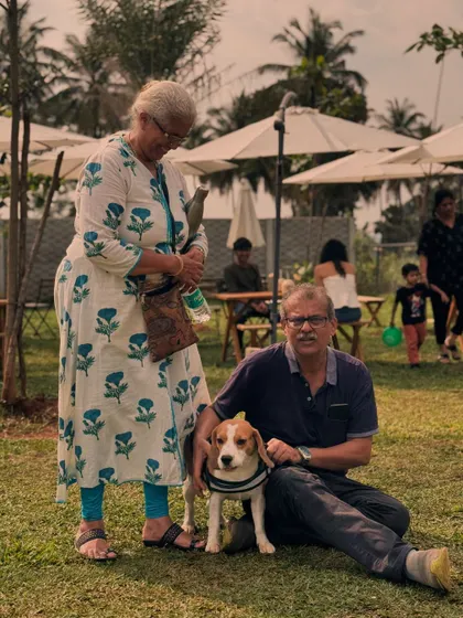 A couple enjoying a peaceful moment on the grass with their adorable Beagle puppy.